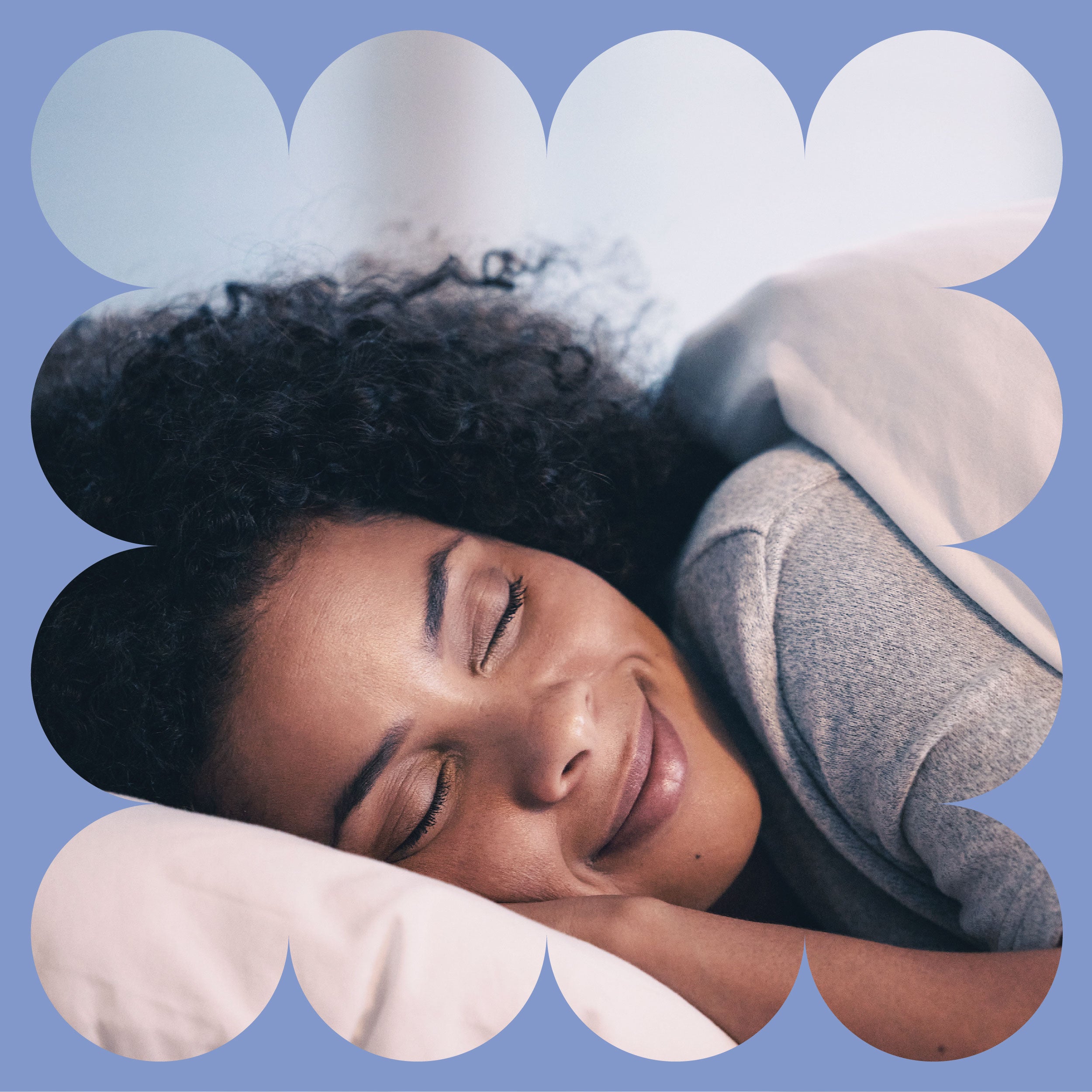 A person with curly hair smiles peacefully while sleeping in bed, resting their head on a pillow. The image is framed by a soft, scalloped blue border.