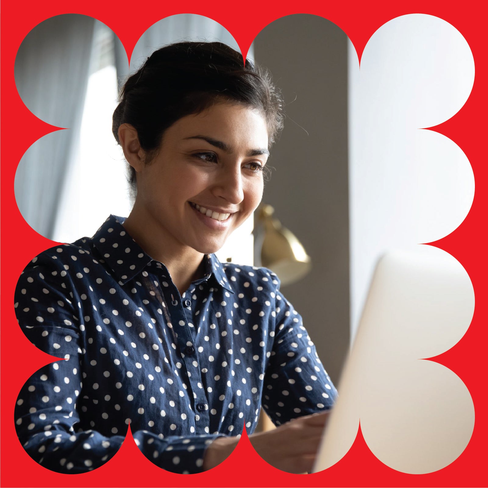 A woman in a blue polka dot shirt smiles while using a laptop. She is indoors with a lamp in the background, framed by a graphic red border with white curved shapes.